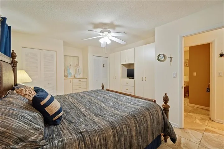 Bedroom with ceiling fan, a textured ceiling, and two closets