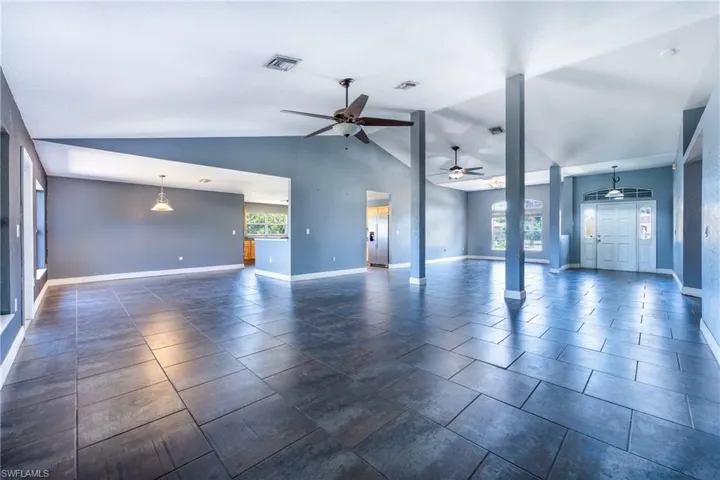 Empty room with plenty of natural light, ceiling fan, and dark tile floors