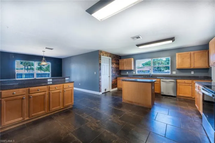 Kitchen featuring stainless steel appliances, sink, dark tile floors, and a kitchen island