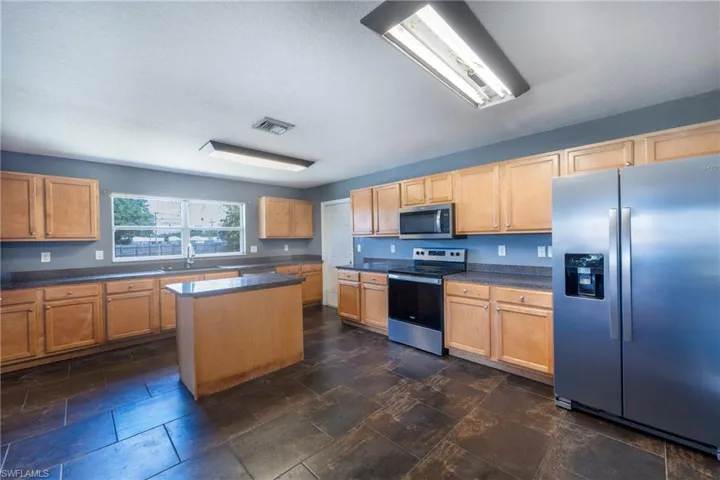 Kitchen featuring sink, a center island, stainless steel appliances, and dark tile floors