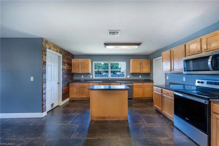Kitchen with dark tile flooring, stainless steel appliances, a textured ceiling, and a kitchen island