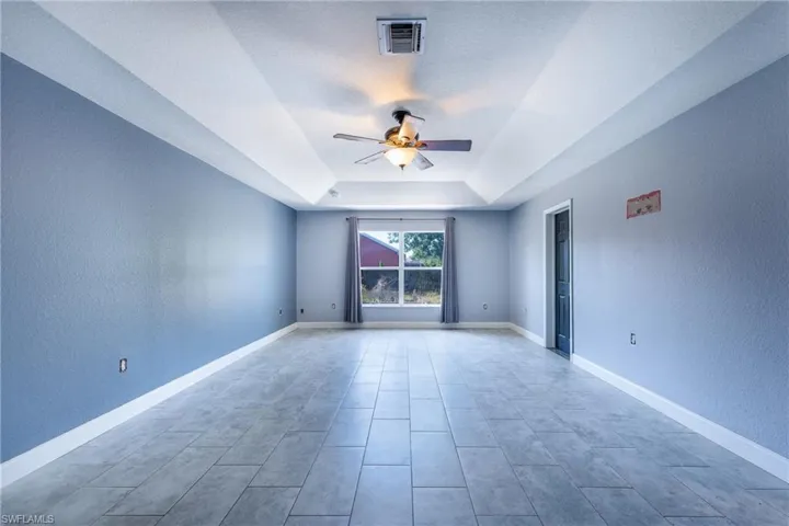 Tiled spare room with ceiling fan and a tray ceiling