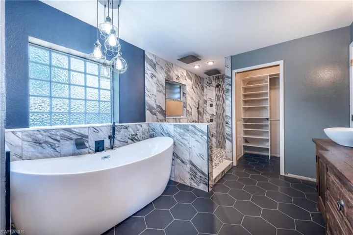 Bathroom featuring tile flooring, shower with separate bathtub, vanity, and tile walls