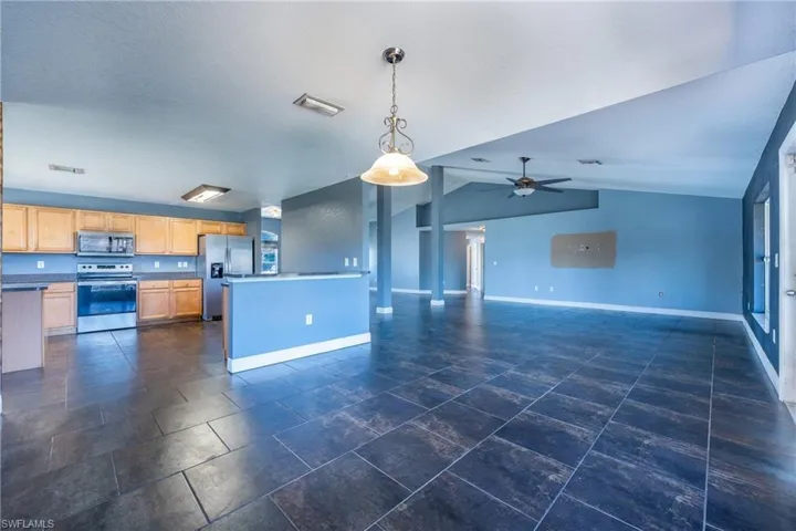 Kitchen with ceiling fan, pendant lighting, dark tile flooring, lofted ceiling, and appliances with stainless steel finishes