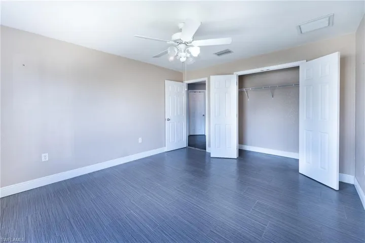 Unfurnished bedroom featuring dark hardwood / wood-style flooring, a closet, and ceiling fan