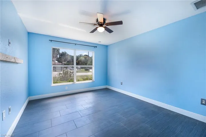 Spare room with ceiling fan and dark tile floors