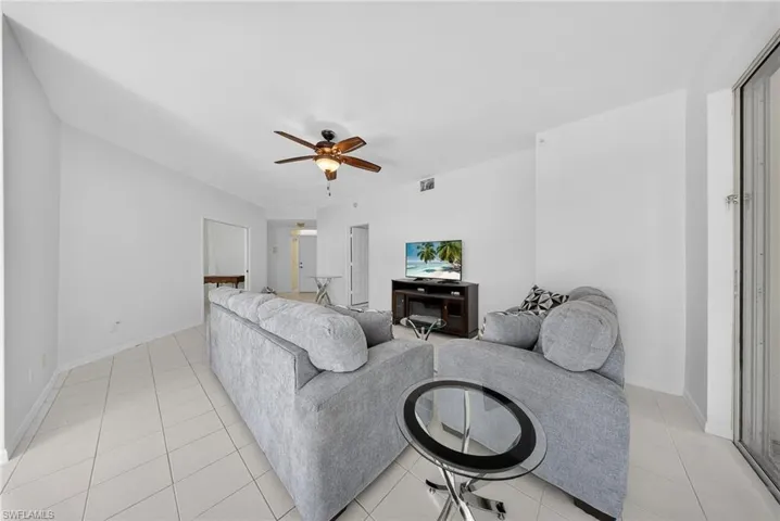 Living room with a ceiling fan and light tile patterned flooring