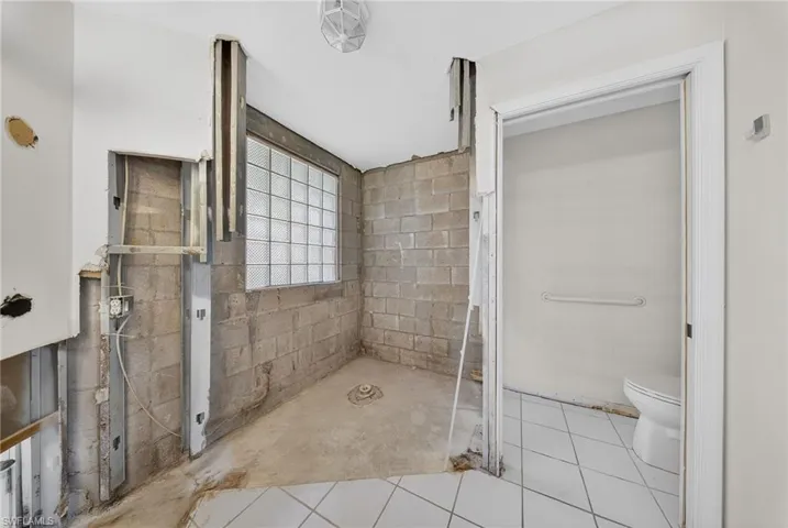 Bathroom featuring toilet and concrete block wall
