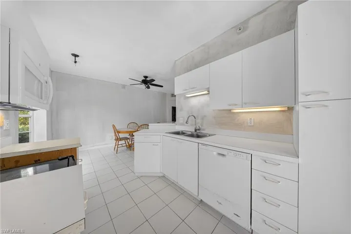 Kitchen featuring light countertops, white appliances, white cabinetry, a ceiling fan, and a peninsula