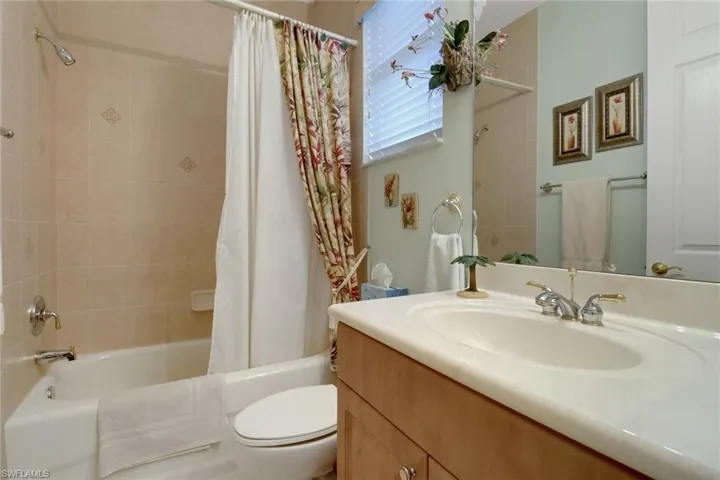 Full bathroom with vanity, shower / tub combo with curtain, and toilet