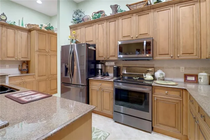 Kitchen with appliances with stainless steel finishes, light stone counters, and light tile patterned floors
