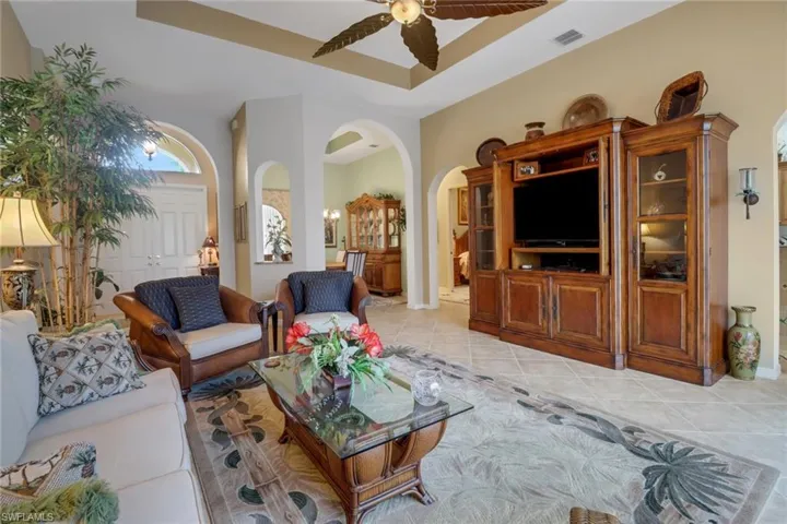 Tiled living room with ceiling fan and a raised ceiling