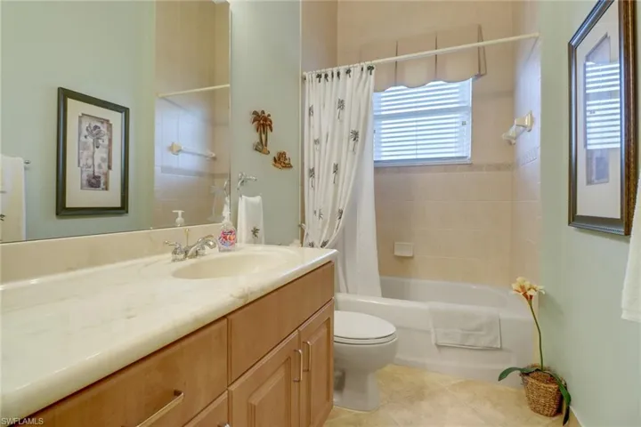 Full bathroom featuring tile patterned flooring, toilet, vanity, and shower / bath combo with shower curtain