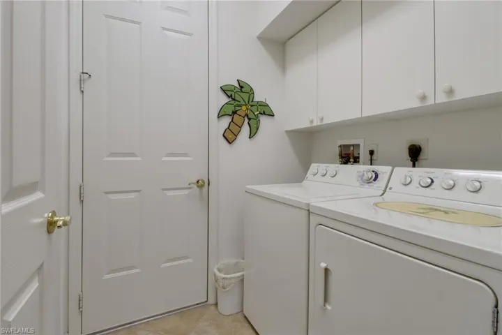 Laundry room featuring independent washer and dryer, light tile patterned floors, and cabinets