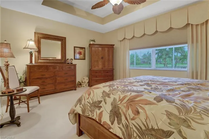 Bedroom featuring a tray ceiling, ceiling fan, and light colored carpet