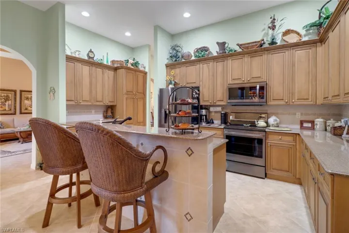 Kitchen with a kitchen bar, light stone countertops, a center island, light tile patterned flooring, and stainless steel appliances