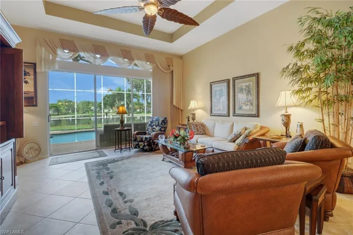 Tiled living room featuring a tray ceiling and ceiling fan