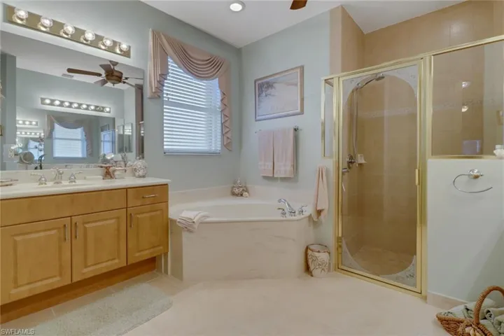 Bathroom with ceiling fan, tile patterned floors, plus walk in shower, and vanity