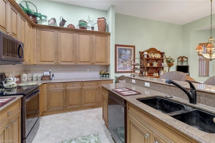 Kitchen featuring sink, light stone counters, electric stove, black dishwasher, and light tile patterned flooring