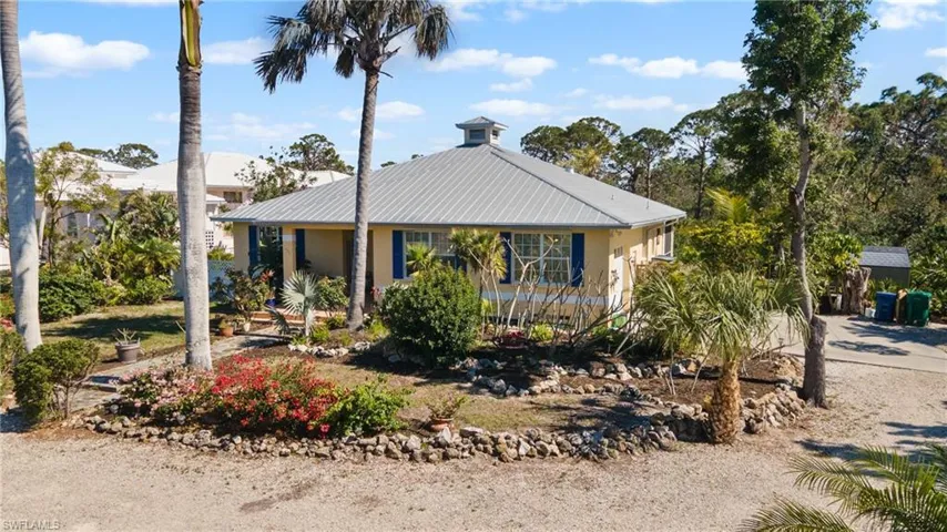 Rear view of property with a sunroom, a metal roof, and a lawn