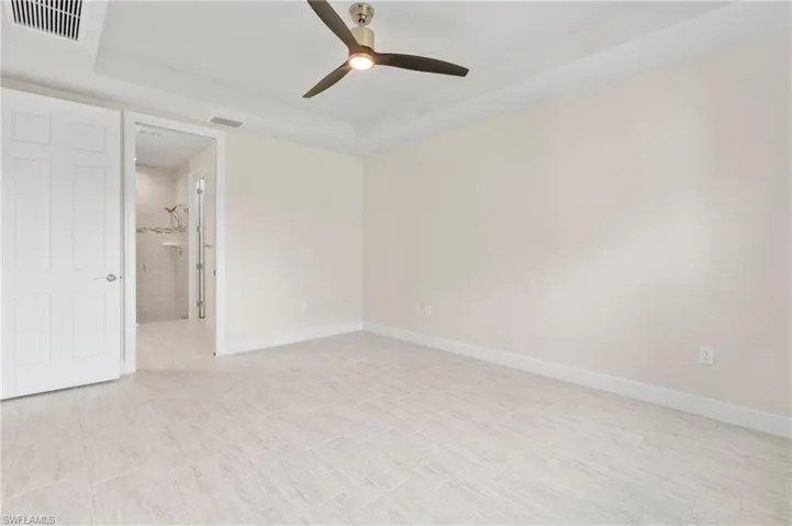 Unfurnished room featuring a tray ceiling, baseboards, ceiling fan, and visible vents