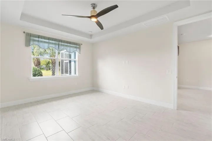 Empty room with baseboards, a tray ceiling, and ceiling fan