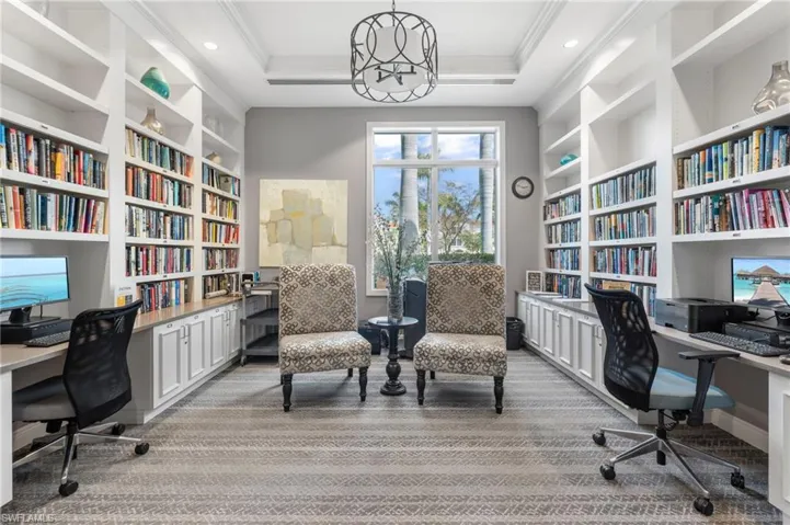 Office area featuring built in study area, a tray ceiling, crown molding, and light colored carpet