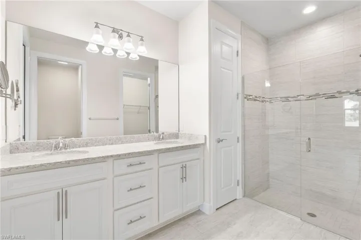 Bathroom with double vanity, a sink, and a shower stall