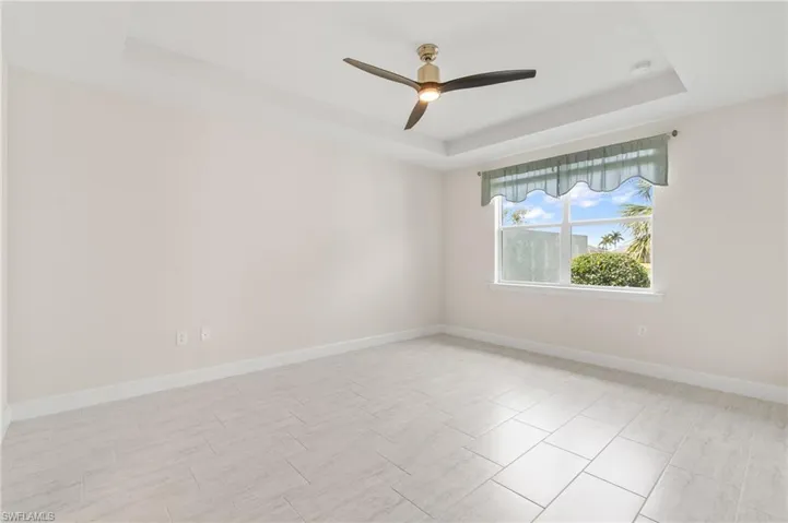 Unfurnished room with a raised ceiling, baseboards, and ceiling fan