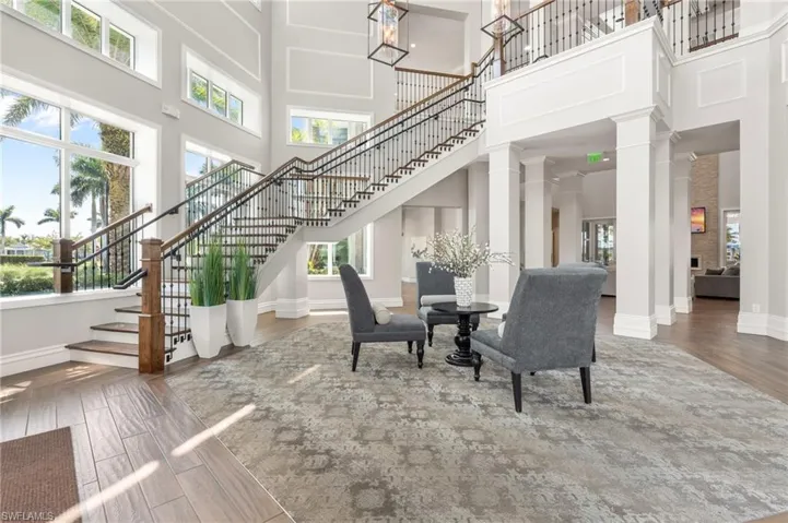 Dining room with stairs, wood finished floors, baseboards, a towering ceiling, and ornate columns
