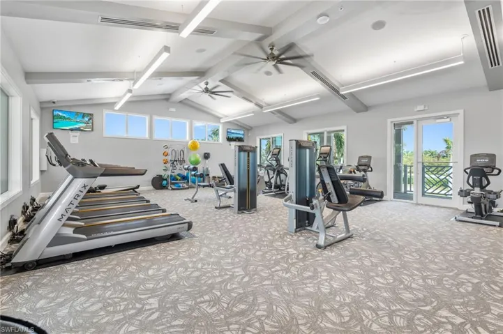 Gym with carpet flooring, visible vents, vaulted ceiling, and a ceiling fan