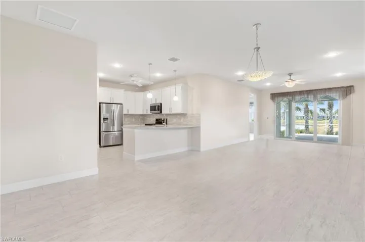 Unfurnished living room featuring baseboards, visible vents, and a ceiling fan
