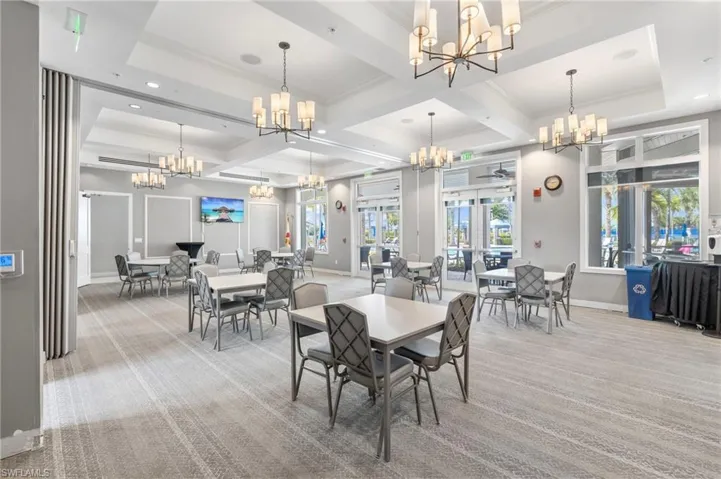Carpeted dining space featuring baseboards, ornamental molding, an inviting chandelier, and coffered ceiling
