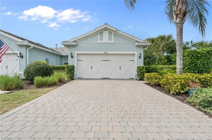 View of front of house featuring a garage, decorative driveway, and stucco siding