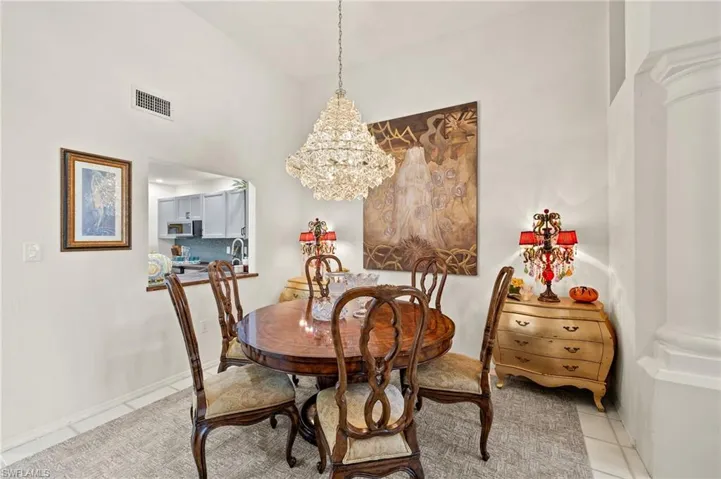 Dining room with a chandelier, visible vents, light tile patterned flooring, and ornate columns
