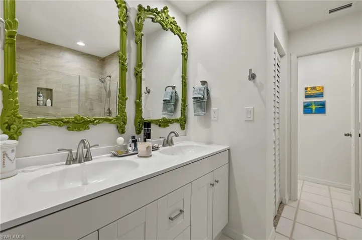 Bathroom featuring tile patterned flooring, a stall shower, visible vents, and a sink