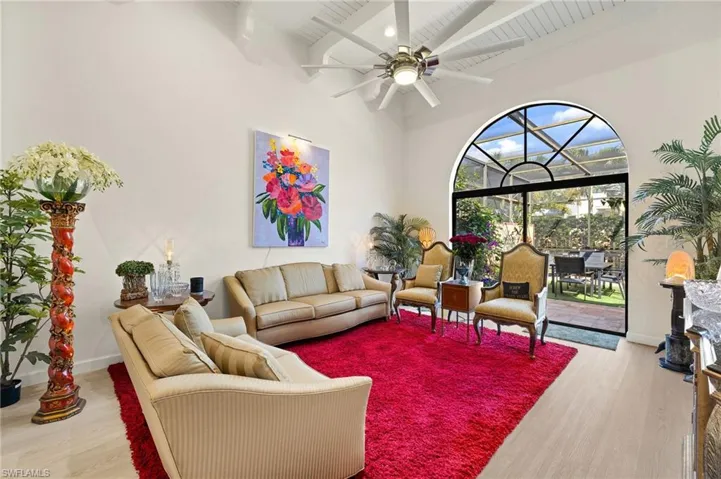 Living area featuring a ceiling fan, beam ceiling, wood finished floors, and high vaulted ceiling
