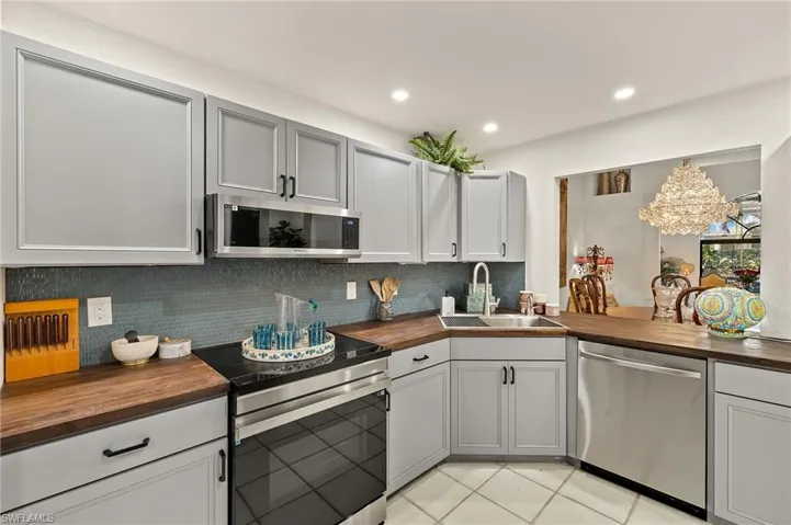 Kitchen featuring a sink, recessed lighting, stainless steel appliances, decorative backsplash, and wooden counters