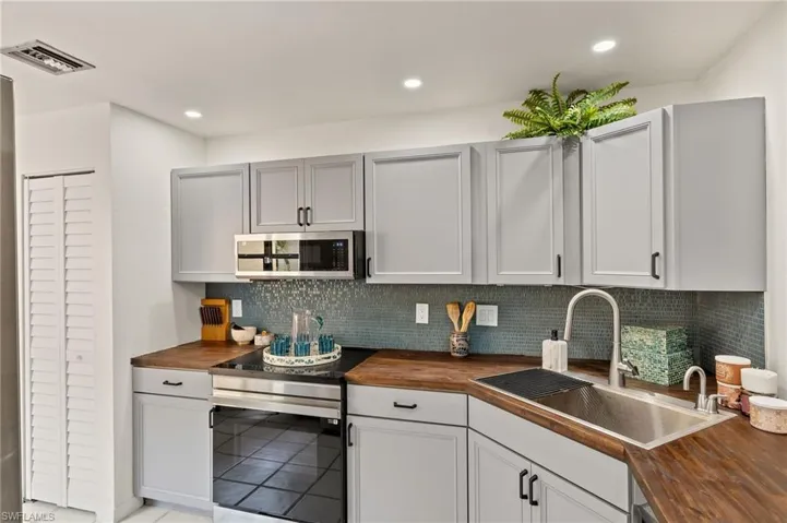 Kitchen with visible vents, a sink, appliances with stainless steel finishes, tasteful backsplash, and butcher block counters