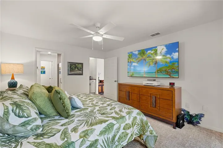 Bedroom with visible vents, light colored carpet, and ceiling fan