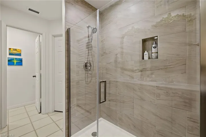Full bath featuring tile patterned flooring, visible vents, and a shower stall