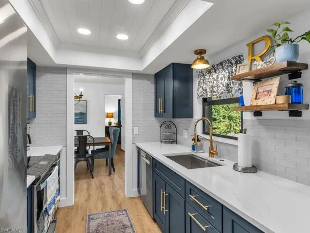 Kitchen featuring blue cabinetry, a raised ceiling, sink, and light hardwood / wood-style floors