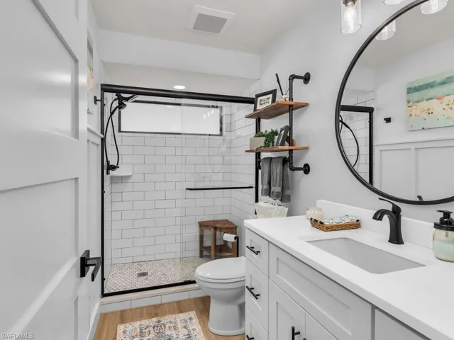 Bathroom featuring vanity, hardwood / wood-style flooring, toilet, and an enclosed shower