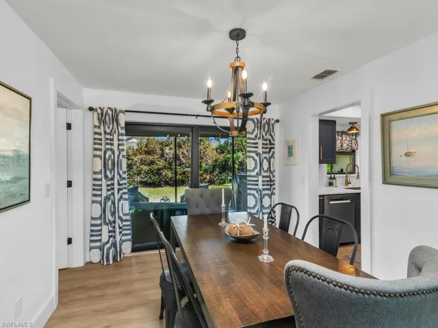 Dining room with sink, light hardwood / wood-style flooring, and an inviting chandelier