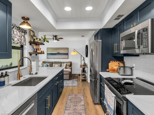 Kitchen featuring a raised ceiling, sink, light wood-type flooring, and stainless steel appliances