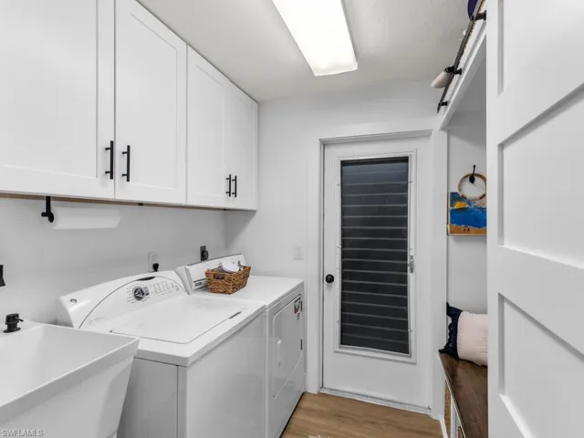 Washroom featuring washing machine and dryer, cabinets, sink, and light hardwood / wood-style floors