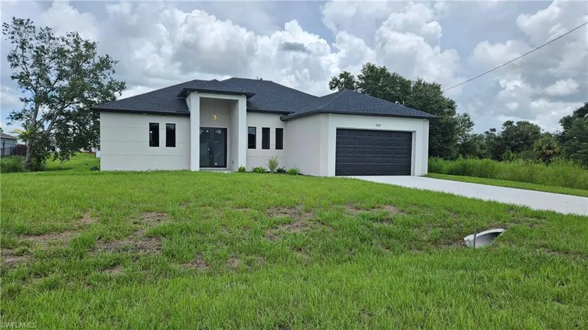 View of front of home with concrete driveway, a garage, a front yard, and stucco siding