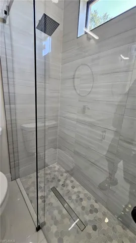 Full bath featuring toilet and a stall shower