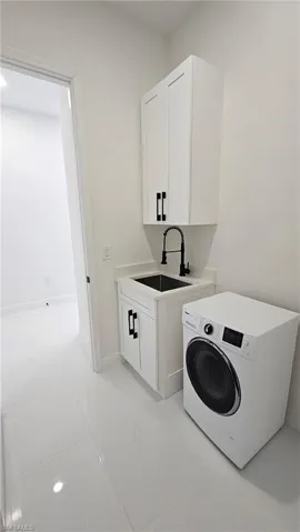 Laundry area with washer / clothes dryer, cabinet space, and light tile patterned floors