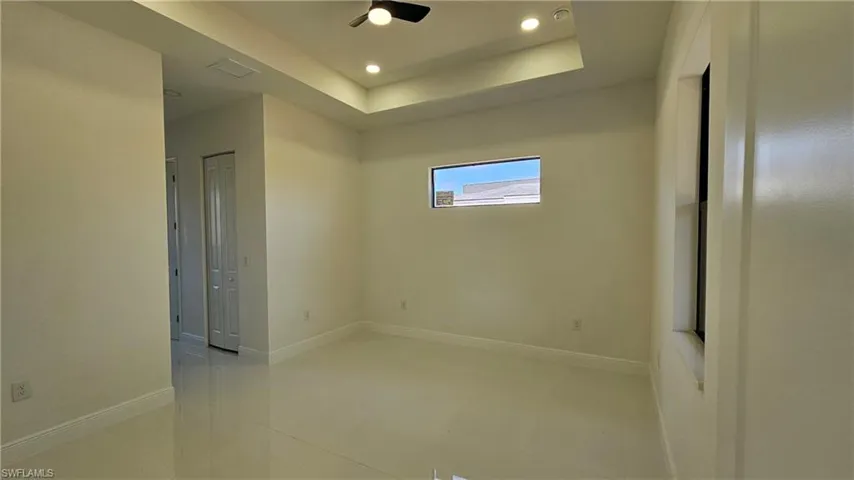 Empty room featuring a tray ceiling, recessed lighting, light tile patterned floors, and a ceiling fan